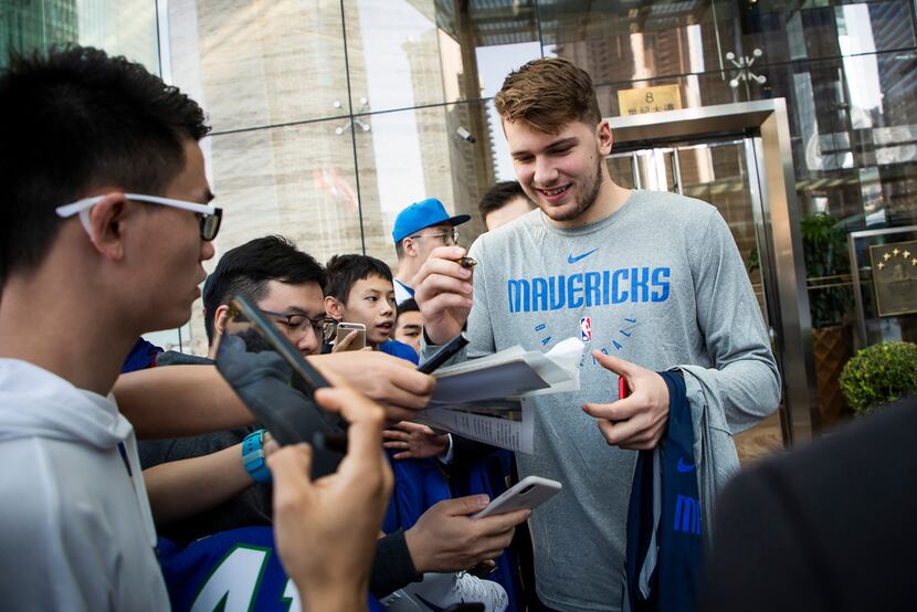 FILE - Dallas Mavericks guard Luka Doncic signs autographs for fans as the team departs...