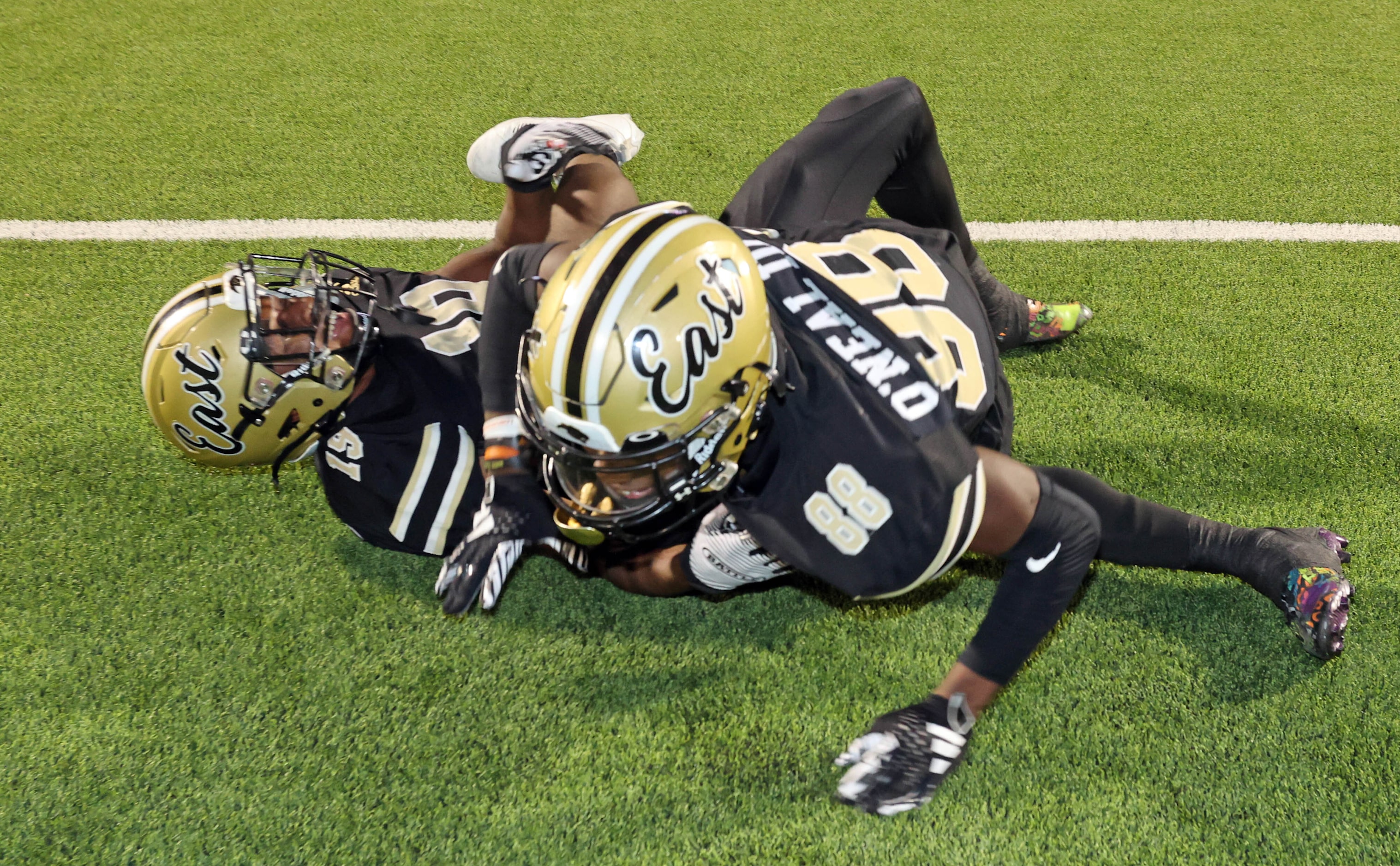 Plano East High players Jaylon Hatcher (19) and Ezra O’Neal III (88) roll on the turf after...