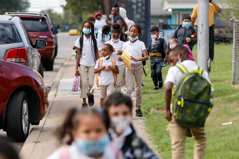 Children walk along a sidewalk after school at Paul L. Dunbar Learning Center in Dallas on...