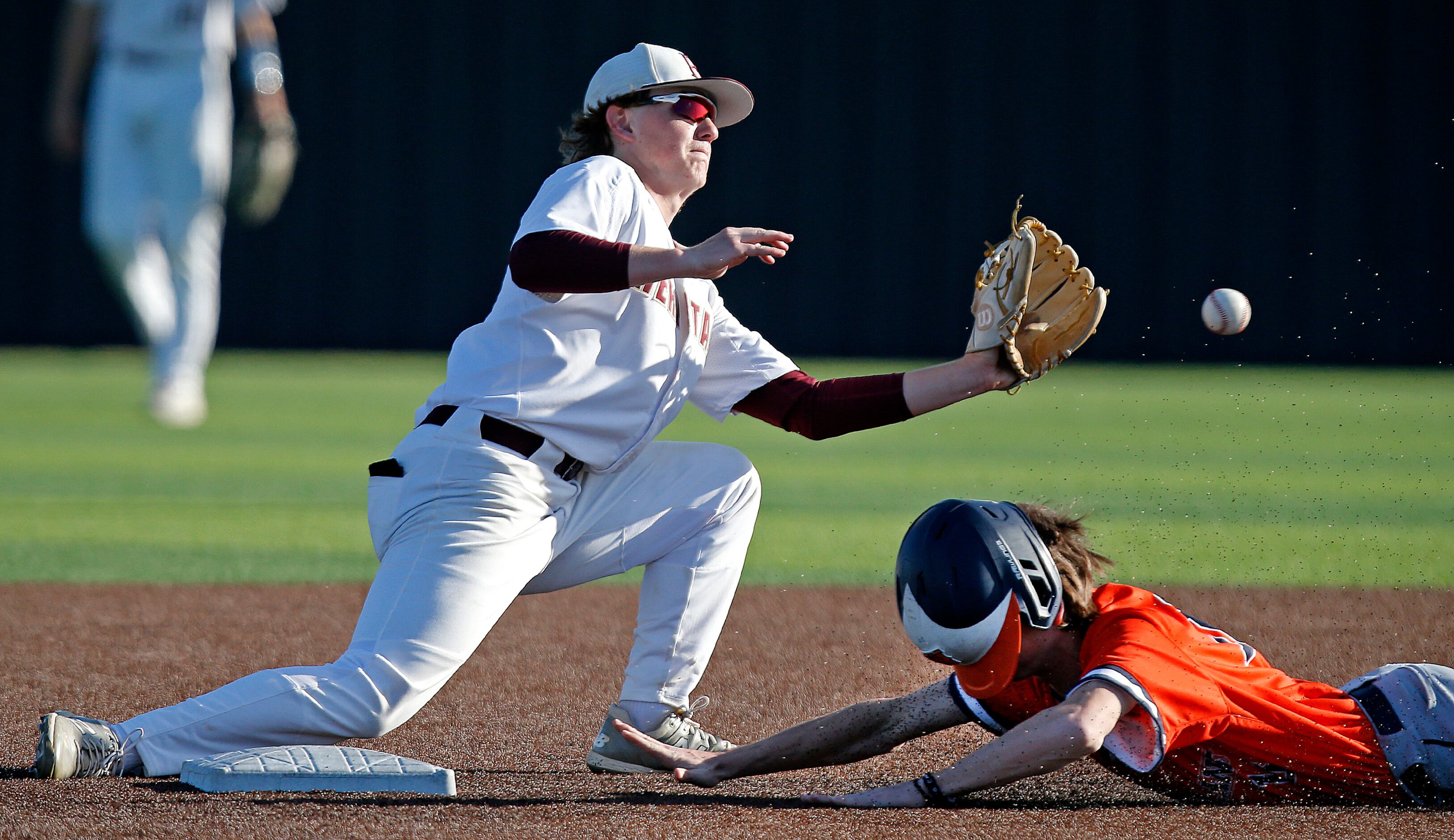 Heritage second baseman Gehrig Butz (14) wasn’t able to put the tag on Wakeland base runner...
