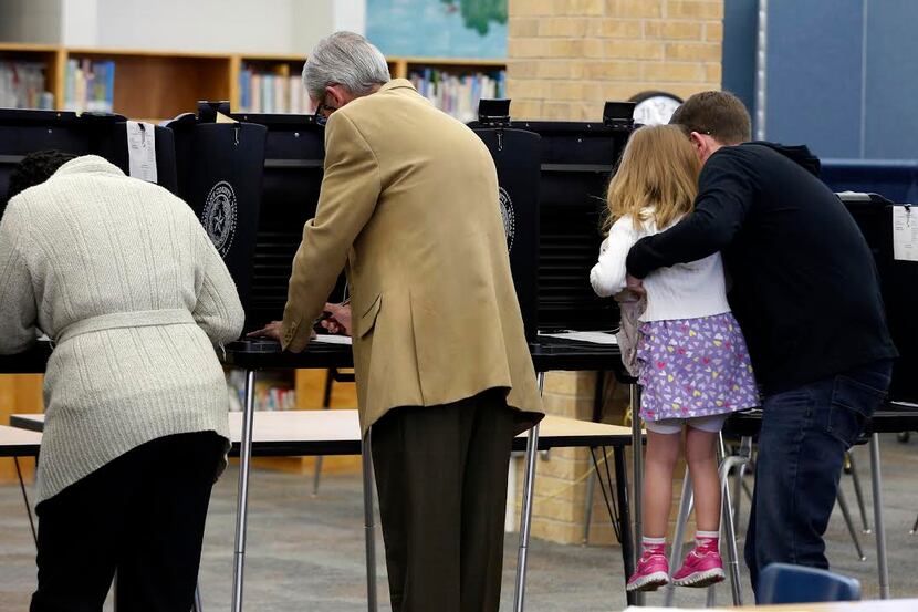 
Joseph Nader lifts his daughter Lydia Nader, 4, as he votes at Sherrod Elementary School in...