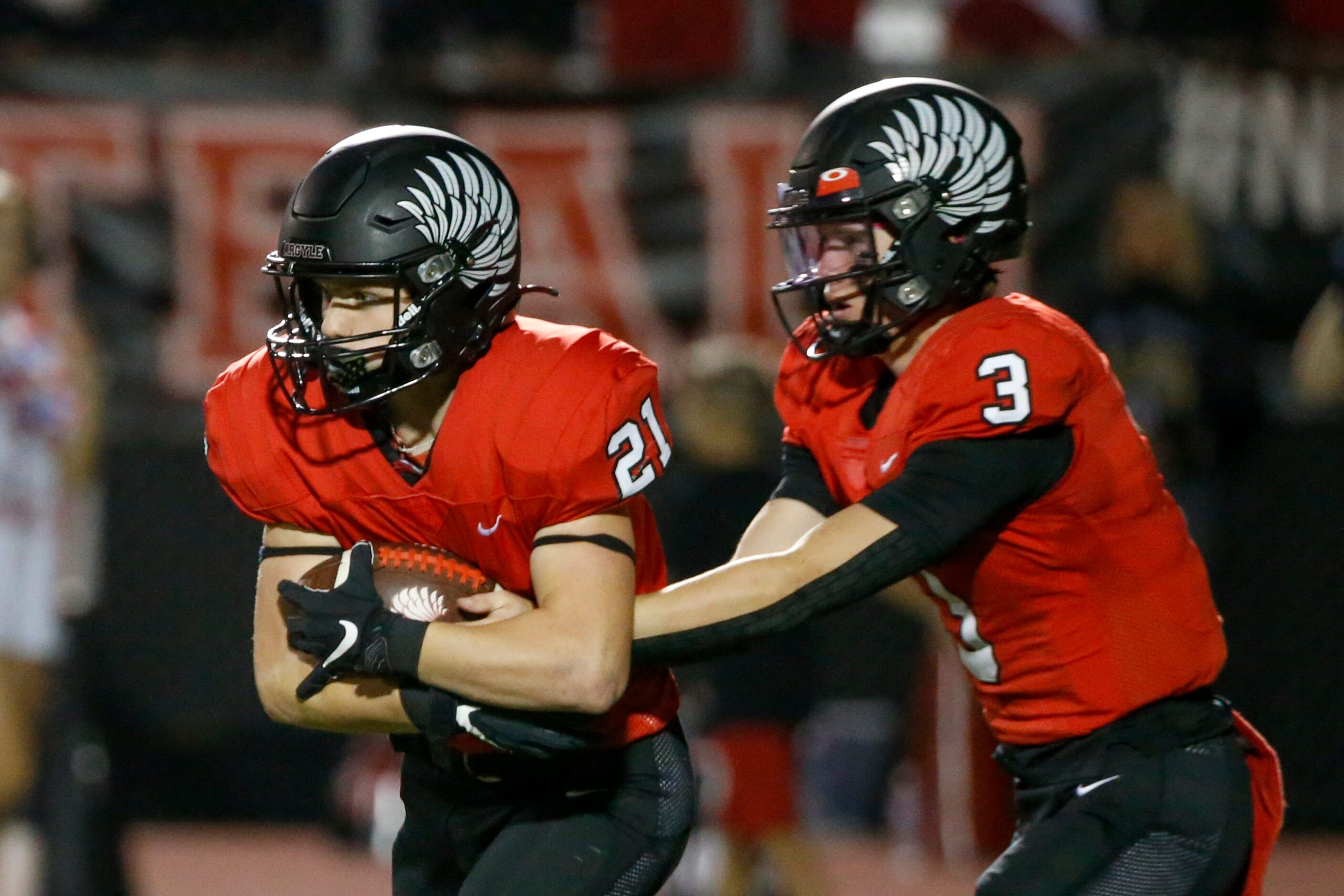 Argyle quarterback Jacob Robinson (3) hands the ball to running back Peyton Shoemake (21)...