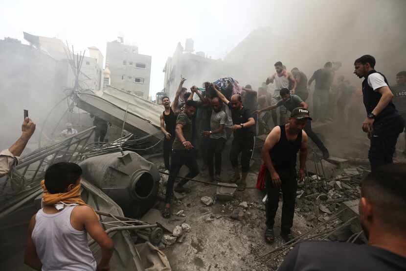 Palestinians remove a body from the rubble of a building after an Israeli airstrike at the...