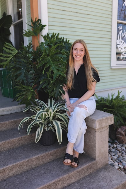 Woman sits alongside steps surrounded by plants