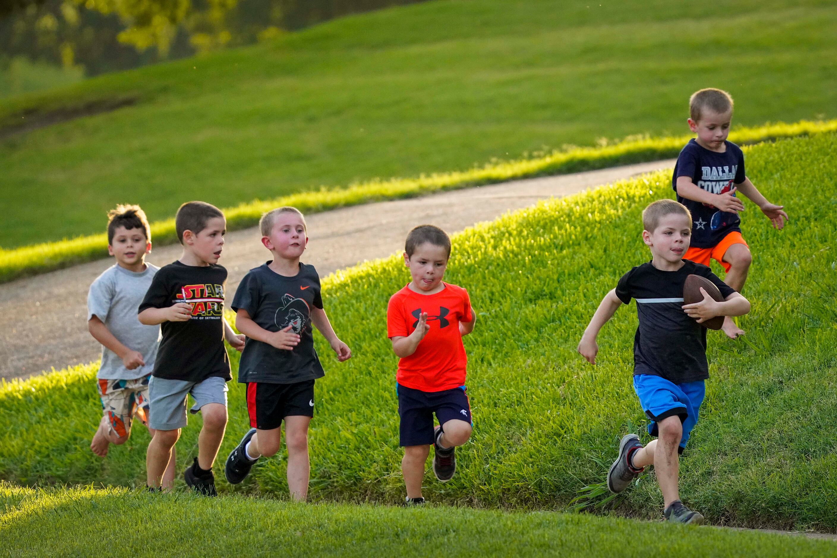 Grant Bass, 6, races down the sidewalk with a football while chased by other neighborhood...