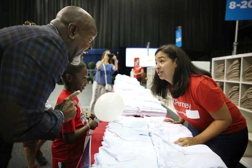 Emmitt Smith helps second-grader Quanta Thompson pick out a free school uniform from...