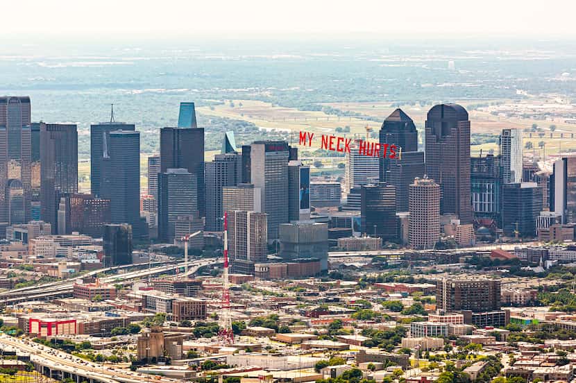 A banner trails behind a plane flying over Dallas, one of five cities included in an aerial...