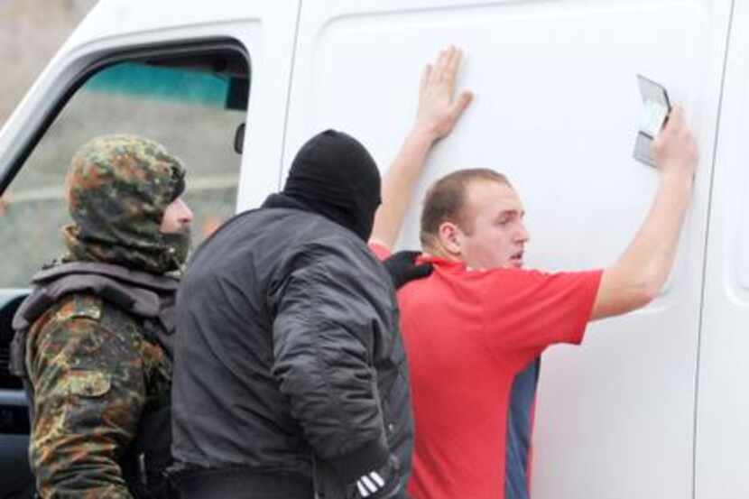 
Armed masked men and local militiamen searched a van driver at a checkpoint on a highway...