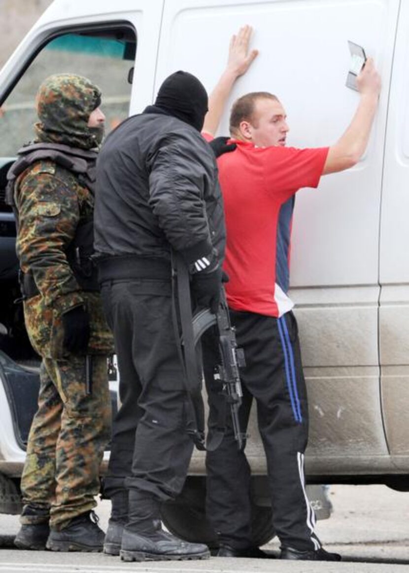 
Armed masked men and local militiamen searched a van driver at a checkpoint on a highway...