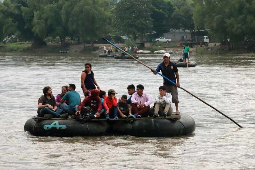 Un grupo de personas cruzan el Río Suchiate en una balsa improvisada desde Guatemala a...