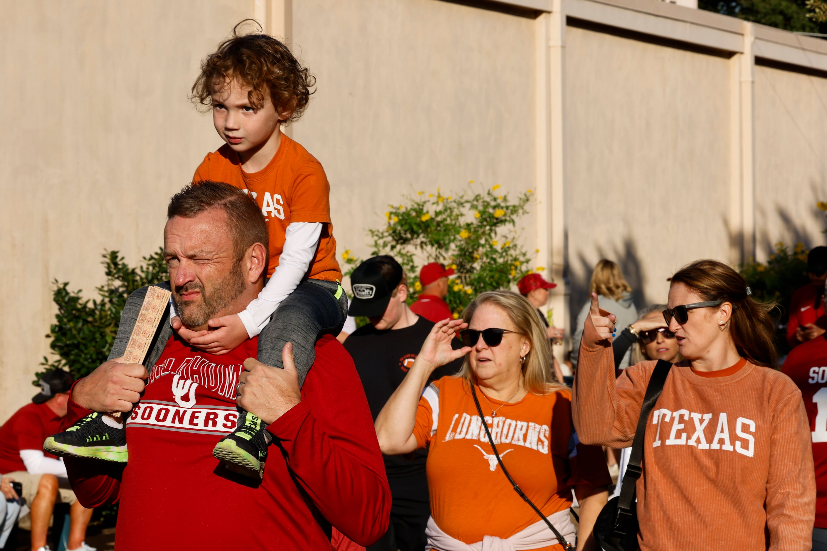 Derek Jones carrying her son Jax, 4, from Oklahoma heads toward the Cottown Bowl ahead of...