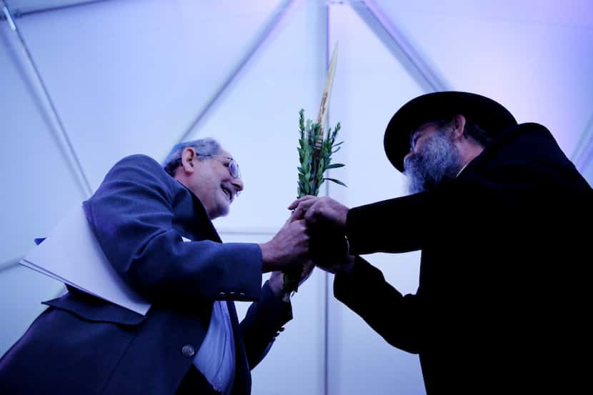 Holocaust survivor Max Spindler (left) holds onto the Lulav while praying with rabbi Mendel...
