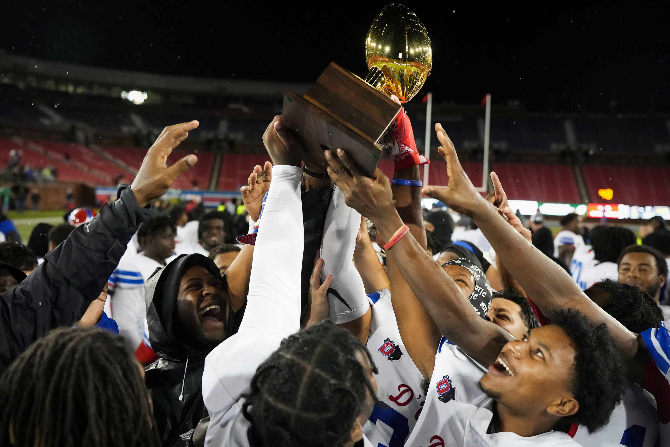 Duncanville players celebrate with the game trophy after a victory over Prosper in a Class...