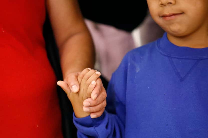On Friday, June 22, a mother (left) and son, from Guatemala, hold hands during a news...
