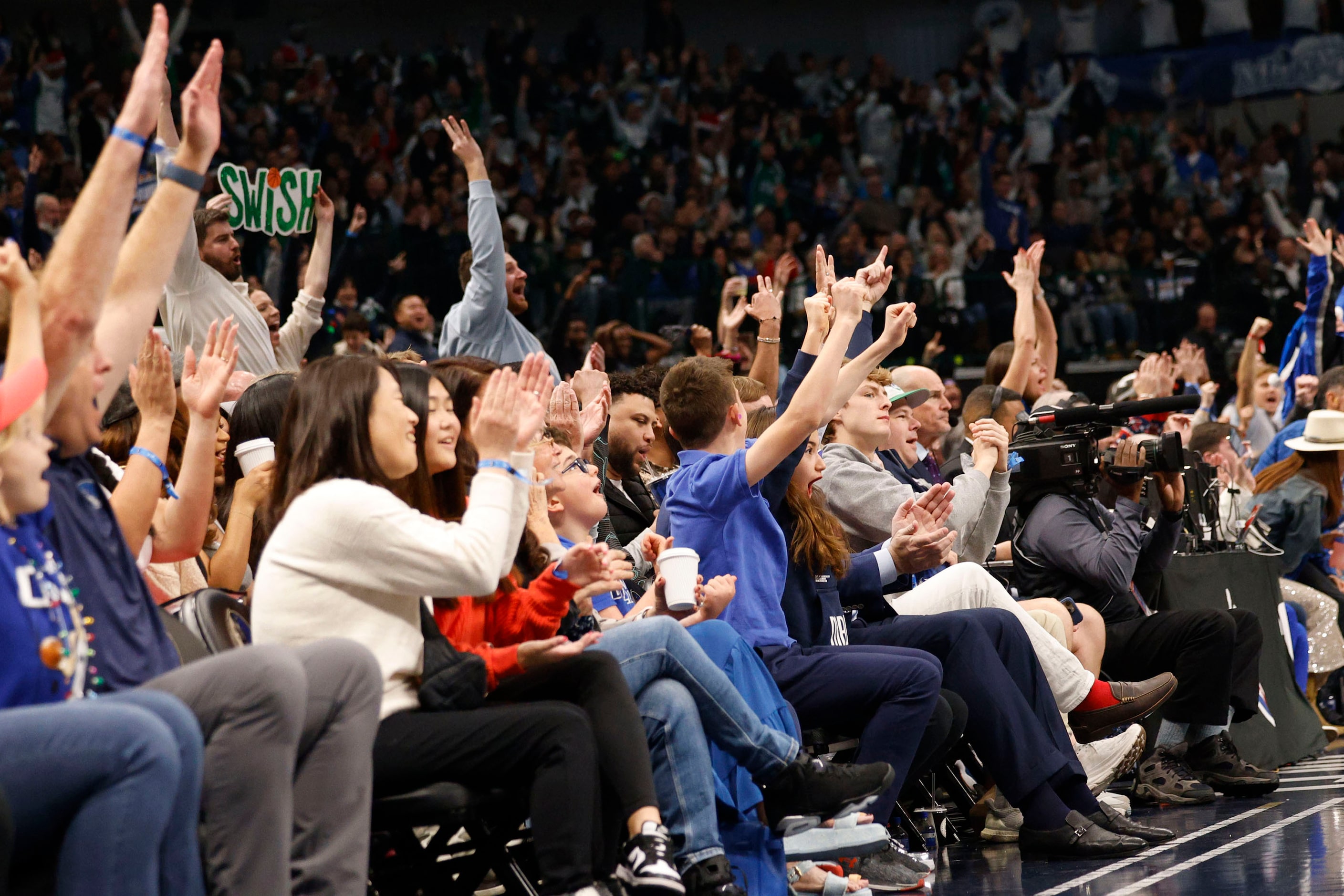 People cheer during the first half of an NBA basketball game between the Dallas Mavericks...