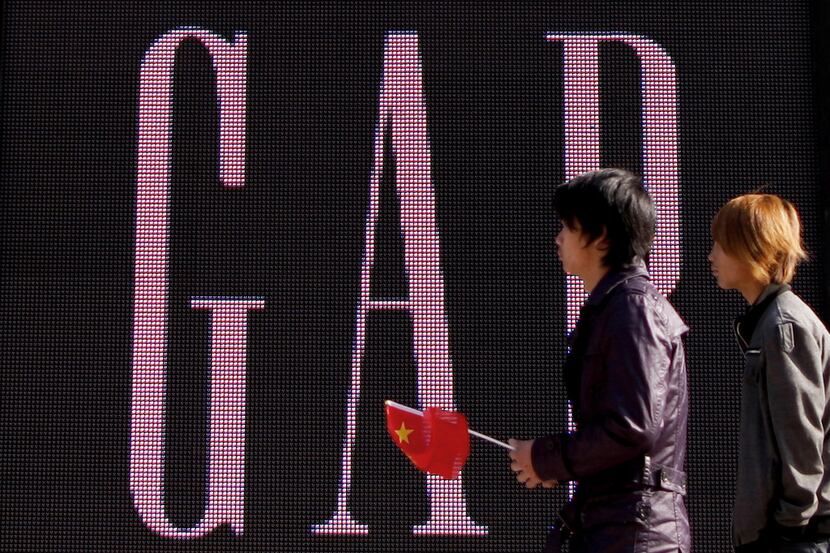 A man carries a Chinese flag as he walks past U.S. retailer Gap's newly-opened flagship...