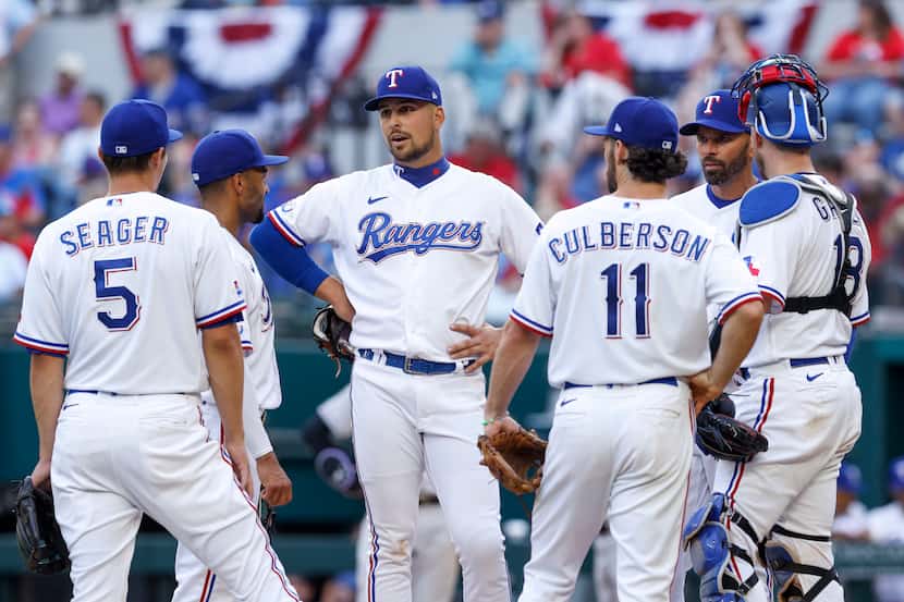 Texas Rangers manager Chris Woodward (second from right) speaks with the infielders during a...