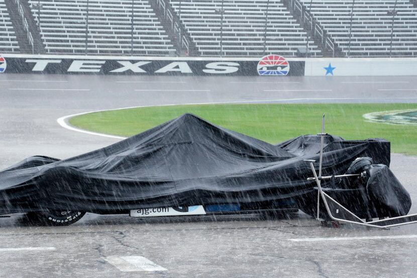 The race car of Max Chilton, from England, is covered by a tarp during a thunderstorm which...