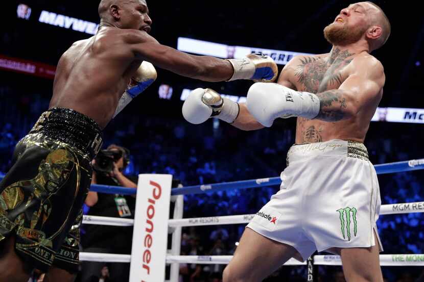 Floyd Mayweather Jr. hits Conor McGregor in a super welterweight boxing match Saturday, Aug....