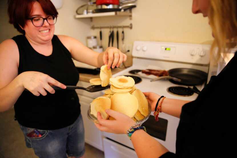 Rebecca Mitts carefully adds more pancakes to the large stack held by Macie Liptoi. The two...