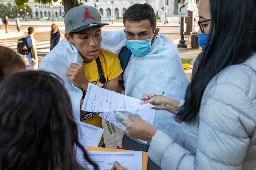 Volunteers help migrants organize their paperwork after they arrived on one of three buses...