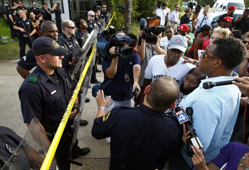 Then-Dallas City Council member Dwaine Caraway (right) tried to calm the emotions of family...