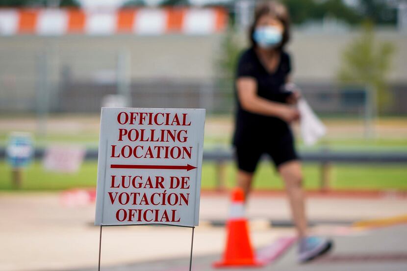 A woman wearing a face mask passes a polling place sign outside a Collin County Early Voting...