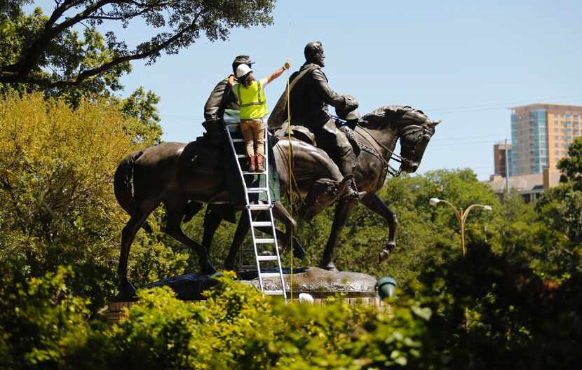 A crewman measures the height of the Robert E. Lee statue as it is prepared for removal from...