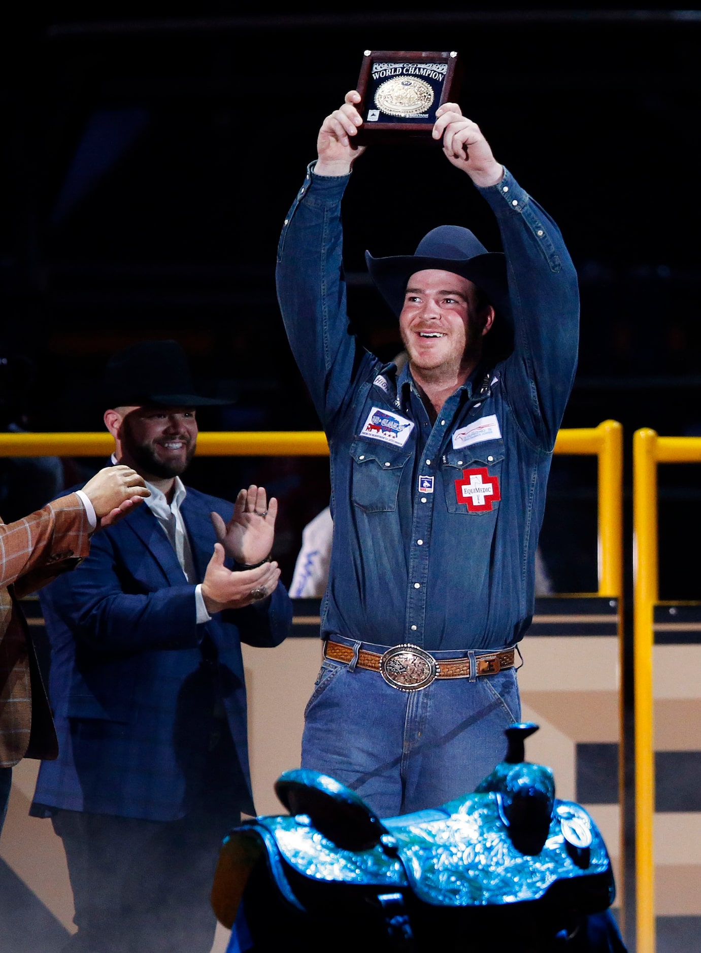 Steer Wrestling World Champion Jacob Edler of State Center, Iowa raises his winning belt...