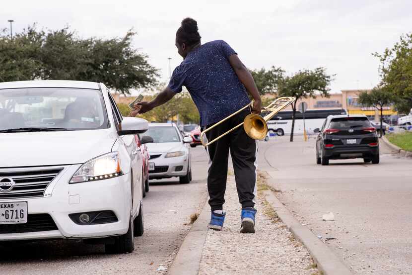 Joshua Reese accepts a tip after playing his trombone while on a road median in West Oak...