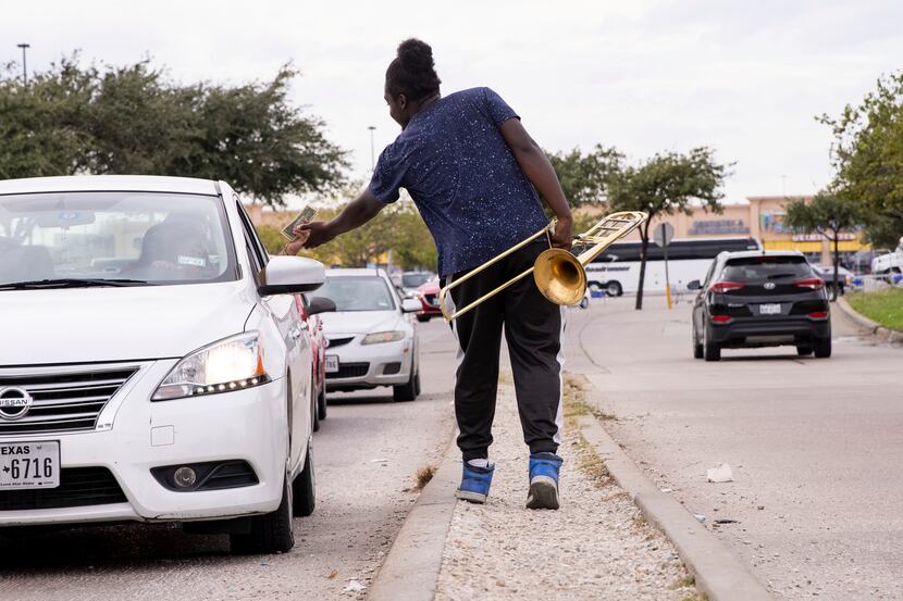 Joshua Reese, 23, accepts a tip while performing his trombone close to the intersection of...