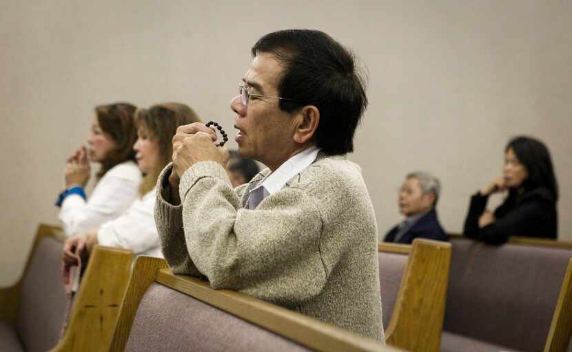 Parishioner An Nguyen prays during an evening mass on Monday at Our Lady of Fatima Church in...