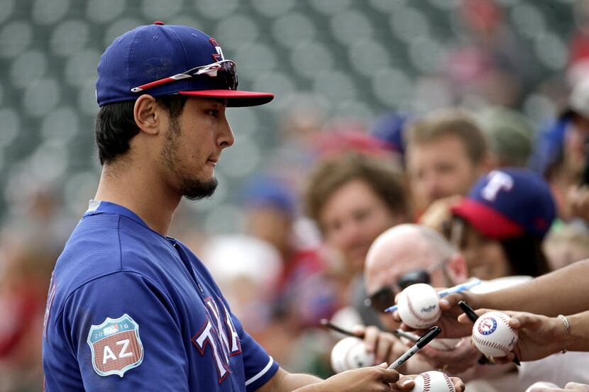 Texas Rangers pitcher Yu Darvish signs autographs before a spring training baseball game...