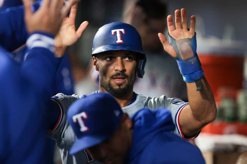 Texas Rangers' Marcus Semien celebrates in the dugout after scoring on a double by Nathaniel...