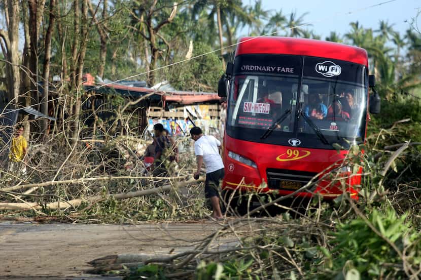 People remove fallen trees from a road in Daanbantayan town, north Cebu, central...