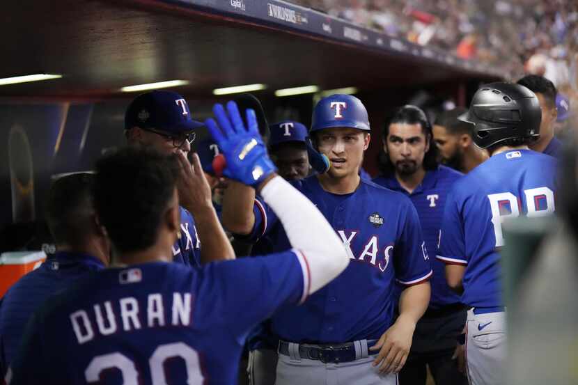Texas Rangers’ Corey Seager, right, is congratulated by teammates after scoring on an RBI...