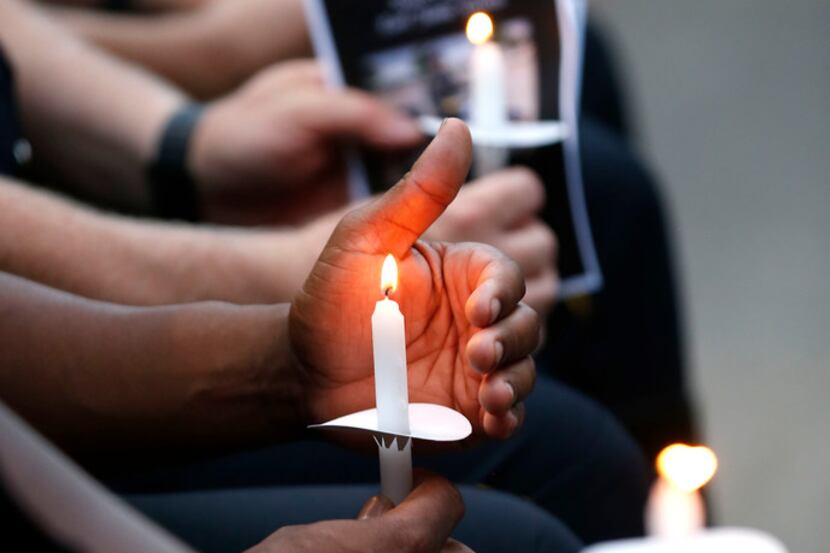 Dallas police officers hold candles during a candlelight vigil for one of their own in this...