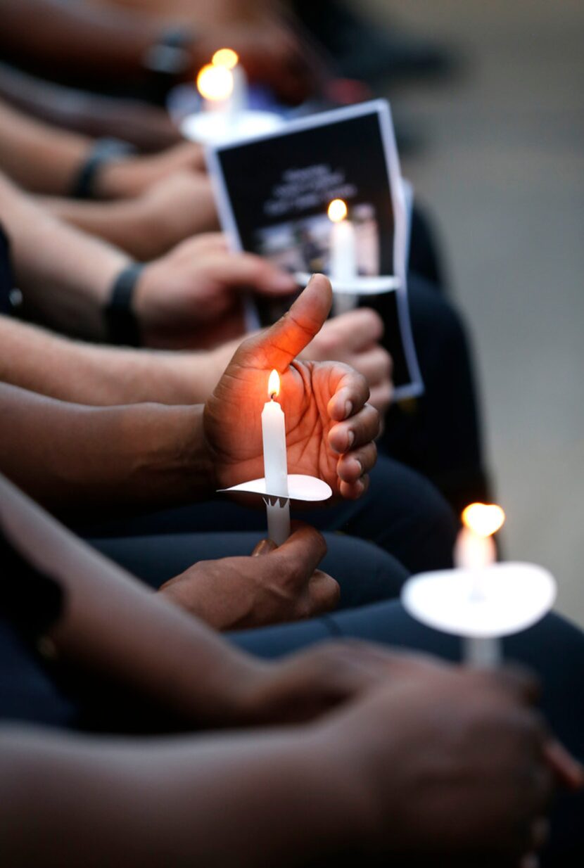 Dallas police officers hold candles during a candlelight vigil for one of their own in this...