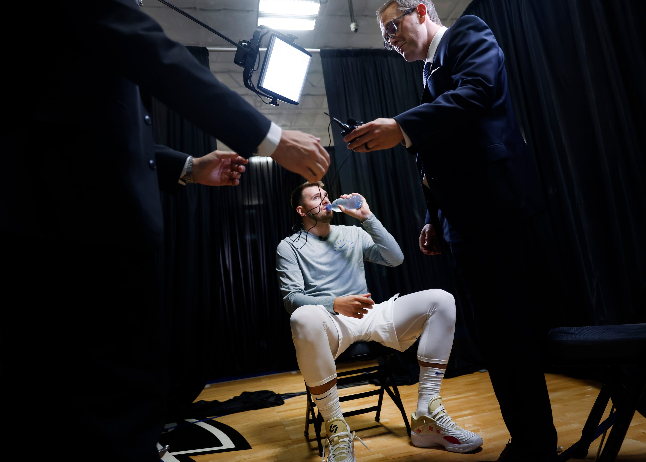 Dallas Mavericks guard Luka Doncic (center)  takes a swig of water between interviews as NBC...