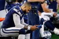 Dallas Cowboys quarterback Dak Prescott (4) looks at a tablet on the bench after he couldn't...