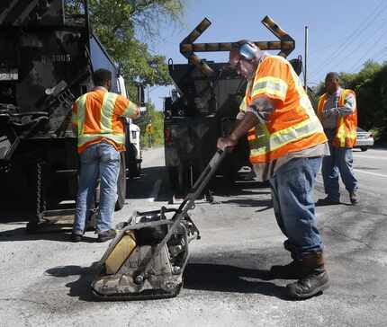  Dallas Street Services employee Ricky King, front, works with others to fix a pot hole on...