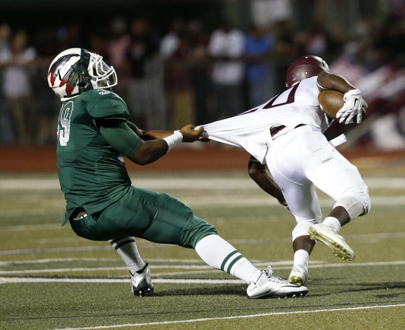 Waxahachie's Keiondre Henderson pulls the jersey of Ennis' Tycen Thompson (20) during...