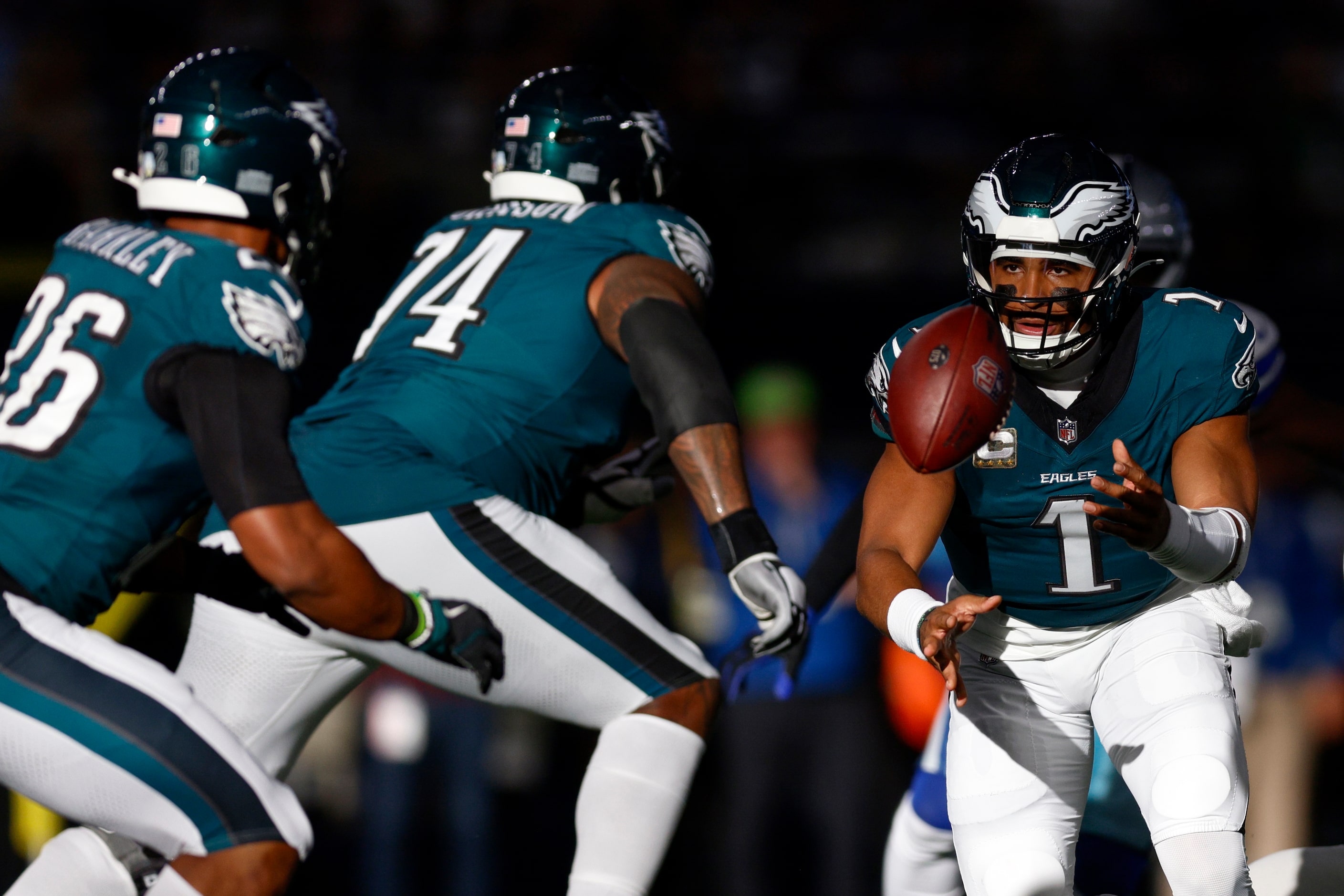 Philadelphia Eagles quarterback Jalen Hurts (1) tosses the ball to running back Saquon...