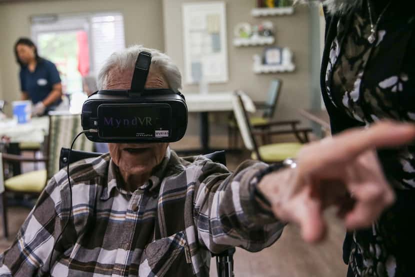 Patrick May, a resident at Signature Pointe assisted living, points as he experiences...