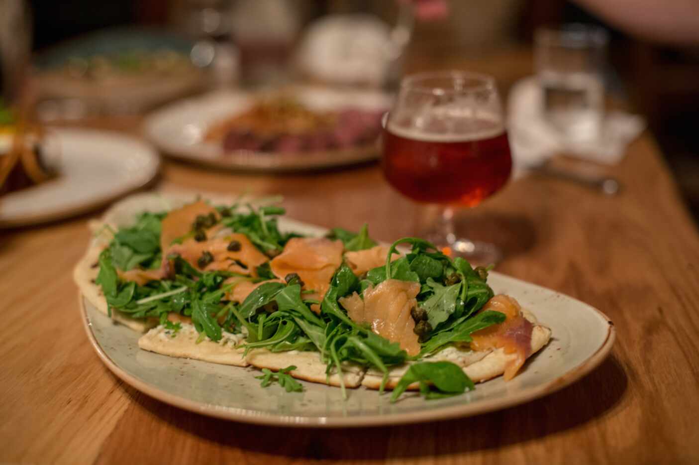 Smoked Salmon Flatbread with capers, boursin, and arugula, at Barley and Board's soft...