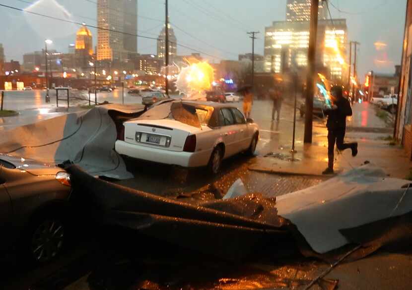 A man runs to his car after a roof fell on to it near First and Greenwood in Tulsa, Okla.,...