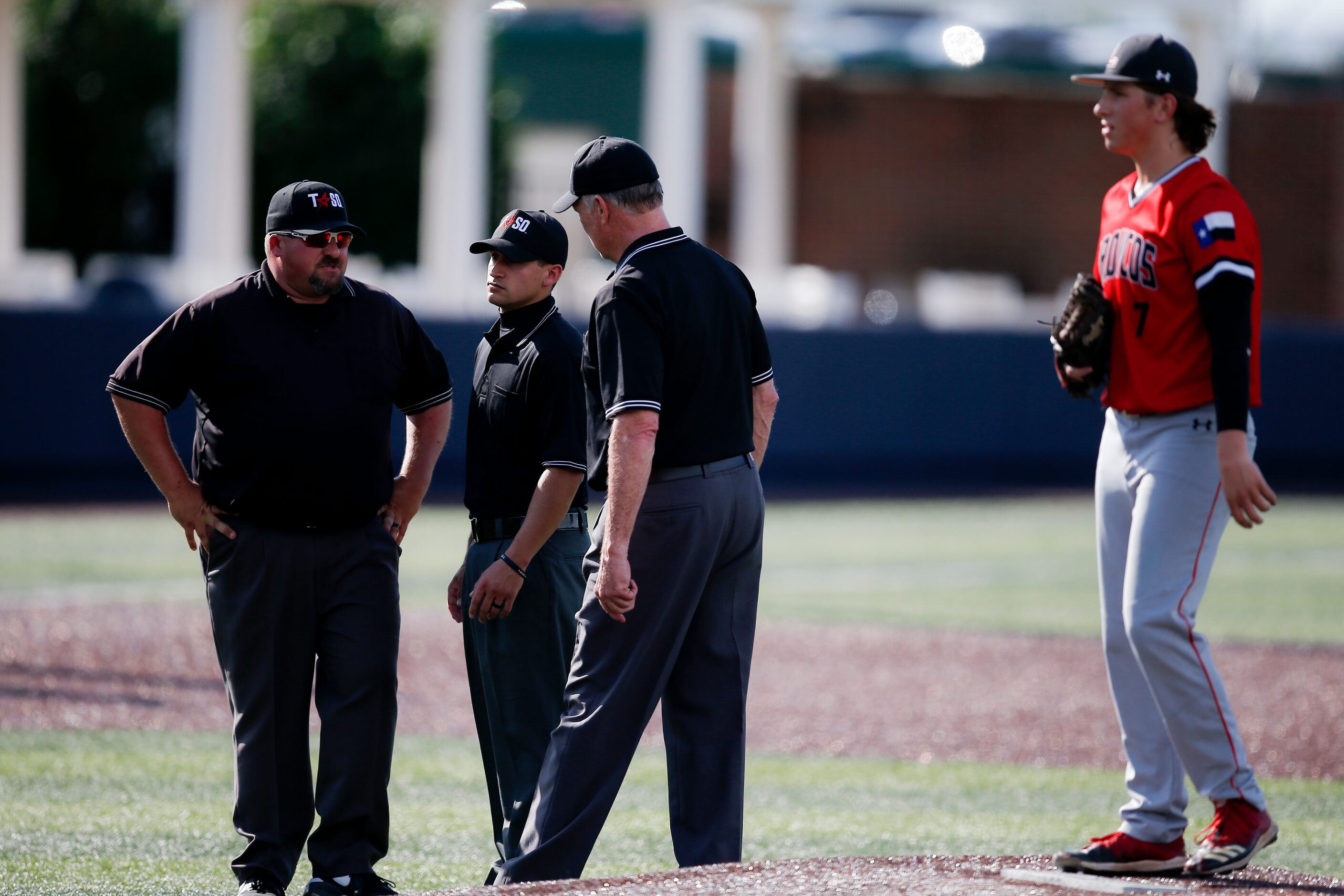 Mansfield Legacy pitcher Drake Dowd, right, looks on as the umpires gather to discuss if...