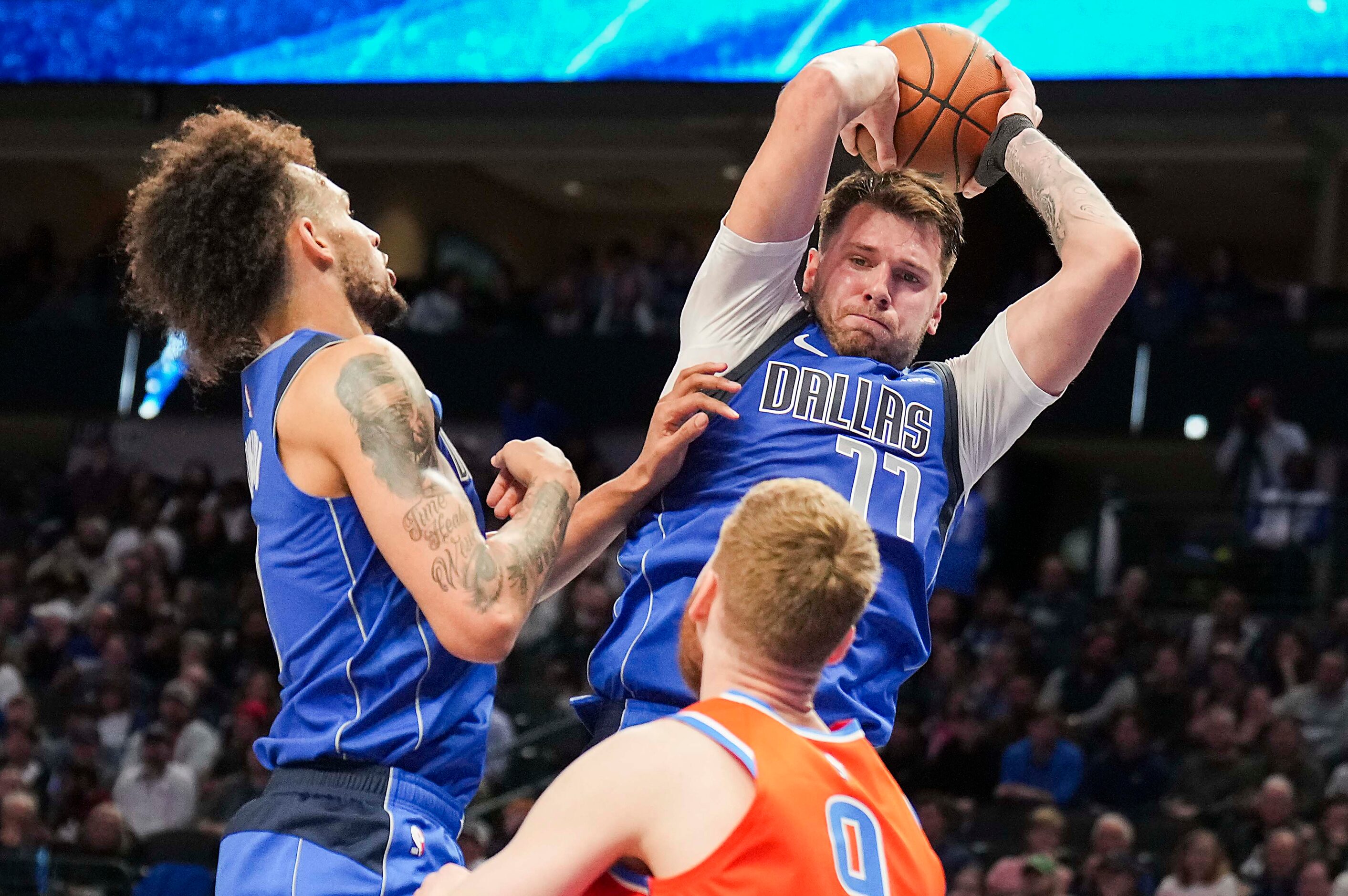 Dallas Mavericks guard Luka Doncic (77) grabs a rebound over Oklahoma City Thunder forward...