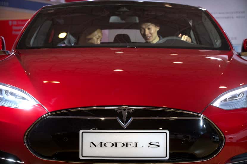In this Monday, April 25, 2016, file photo, a man sits behind the steering wheel of a Tesla...