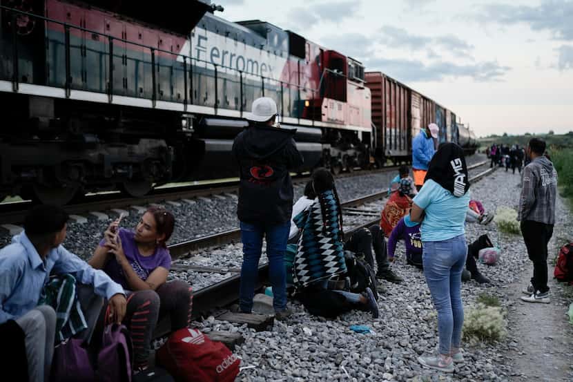 Migrants watch a train pass as they wait along the tracks in Huehuetoca, Mexico, hoping to...